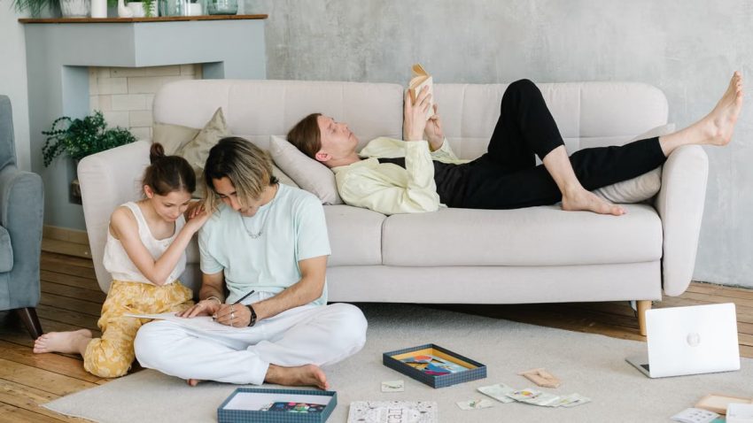 Father and daughter bonding in cozy living room with books and games, creating joyful family moments.